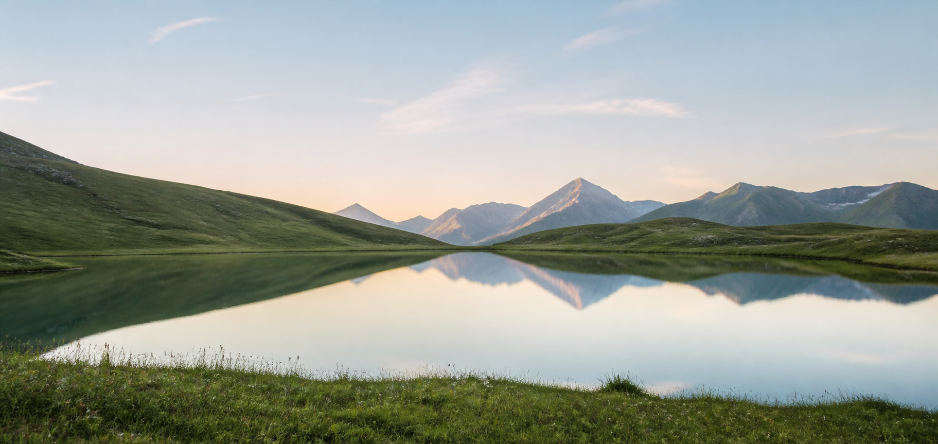 A still mountain lake reflecting the peaks at sunrise